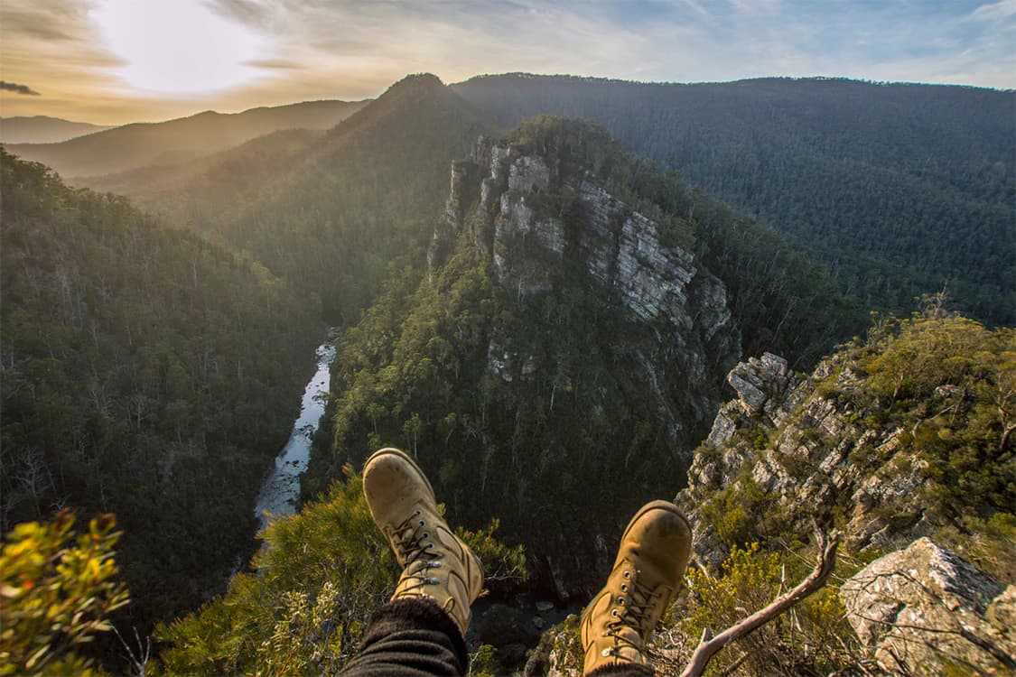 Boots at the edge of a forested mountain viewpoint in a Wyld photograph