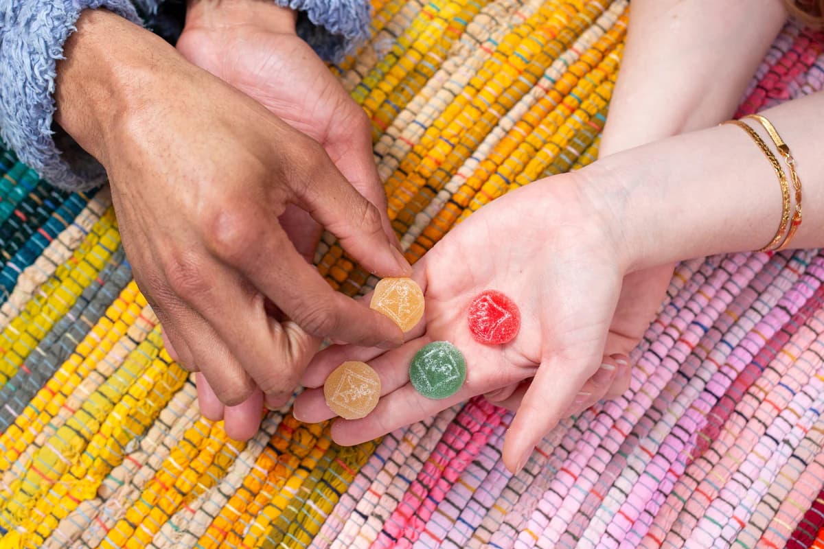 Hands holding colorful Dixie gummies over a woven picnic blanket
