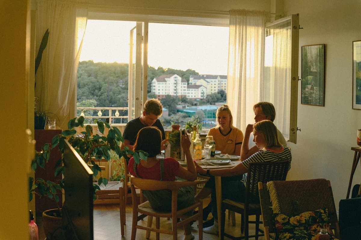 Adults sharing a meal around a table in a sunlit dining room.